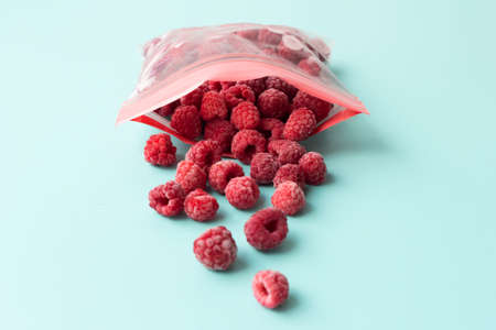 Frozen raspberries are poured out of a zippered plastic bag. Preservation for the winterの写真素材