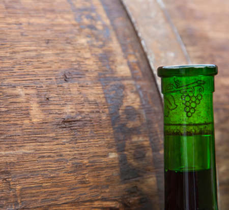 The bottle of wine on the background of oak barrelの写真素材