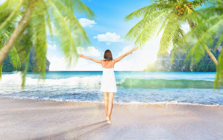 Young girl enjoys a tropical island with palm trees and sunの写真素材