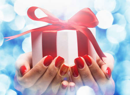 Christmas gift in female hands on bokeh backgroundの写真素材