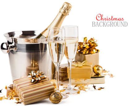 Glasses of champagne with gifts and balls on white backgroundの写真素材