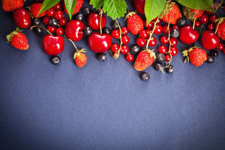 Fresh juicy berries with green leaves on purple backgroundの写真素材