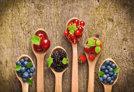 Berries in wooden spoons on wood textureの写真素材