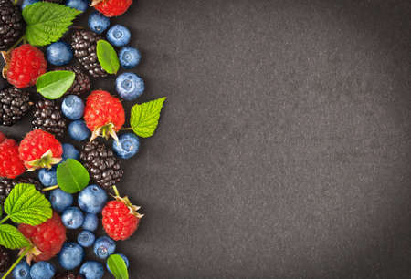Fresh juicy berries with green leaves on dark backgroundの写真素材