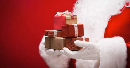 Santa Claus with gifts on red backgroundの写真素材