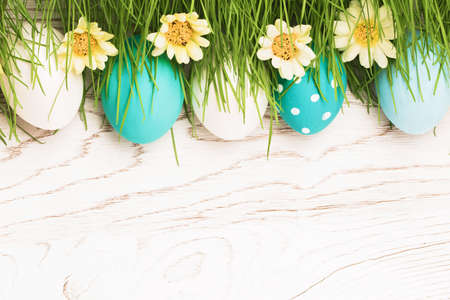 Easter Eggs with green grass on white wooden background