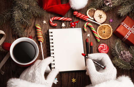 Santa Claus with open notepad on wooden tableの写真素材