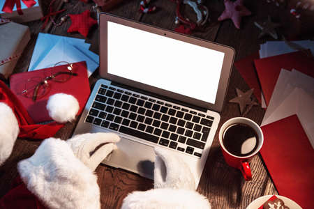 Santa Claus working on computer. Open laptop with white screen conceptの写真素材