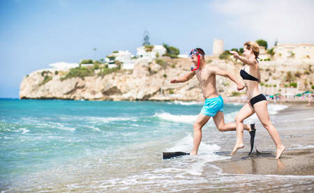 Young couple running on sea beach at sunsetの写真素材