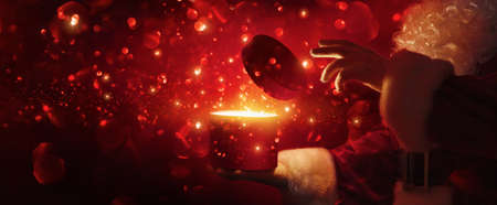 Santa Claus with magic box and snow on red backgroundの写真素材