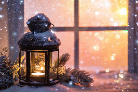 Winter decoration with a candlestick near the snow-covered windowの写真素材