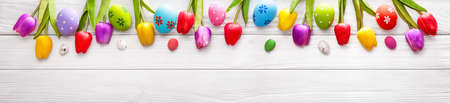Easter Colored Eggs with Flowers on White Wood Backgroundの写真素材