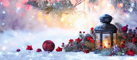 Christmas lantern on snow with fir branch in the sunlight. Winter decoration backgroundの写真素材