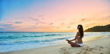 Yoga Concept. Woman Practicing Lotus Pose on Beachの写真素材