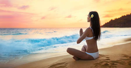 Yoga Concept. Woman Practicing Lotus Pose on Beachの写真素材