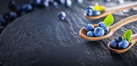 Freshly Picked Blueberries on Dark Slate Background. Juicy and Fresh Blueberries with Green Leaves. Concept for Healthy Eatingの写真素材
