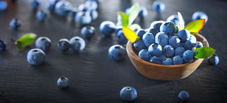 Freshly Picked Blueberries on Dark Slate Background. Juicy and Fresh Blueberries with Green Leaves. Concept for Healthy Eatingの写真素材