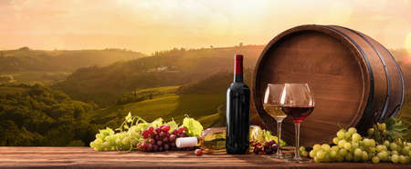 Bottles And Wineglasses With Grapes And Barrel On A Sunny Background. Italy Tuscany
