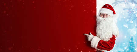 Santa Claus Holding Blank Advertisement Banner Red Background with Copy Spaceの写真素材