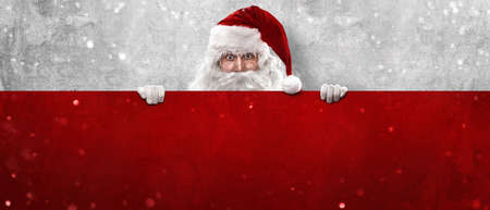 Santa Claus Holding Blank Advertisement Banner Red Background with Copy Spaceの写真素材