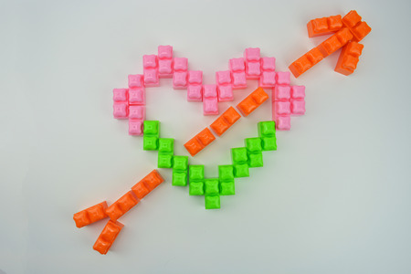 Heart pierced by an arrow made from multicilored constructor blocks. The symbol of broken heartの写真素材