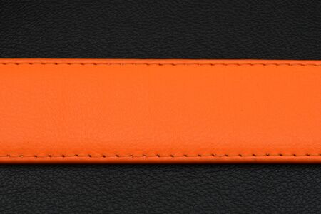 Orange belt on black background. Belt from skin. Belt with orange color. Middle position on backgroundの写真素材