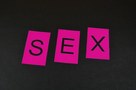 Pink word "Sex" on black background. Word from isolated letters. Pink letters for word Sexの写真素材