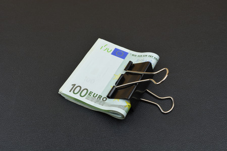 Euro with black clips. Big metal clips with european money on black backgroundの写真素材