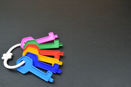 Collection of plastic keys on gray background. Keys with plastic ring. Place your text