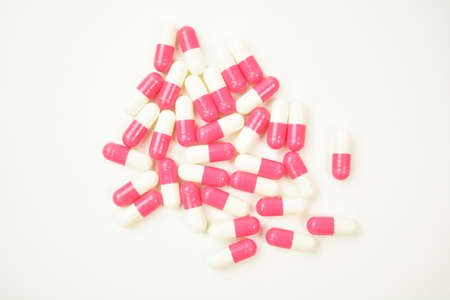 A pile of pills on white background. Red and white pissl. Pills for sport training. Pills for medicineの写真素材