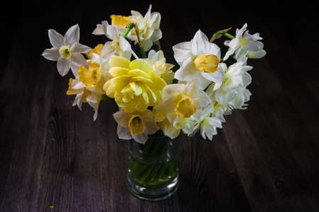 A bouquet of flowers on a dark wooden background. White narcissus in a vase. Flower gift concept....