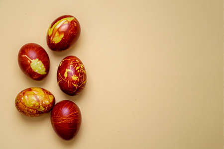 Chicken eggs colored with old-fashioned natural method by onion husks isolated on light brown. Topview of brown eggs with different natural patterns with copyspace. Traditional Easter concept.の写真素材