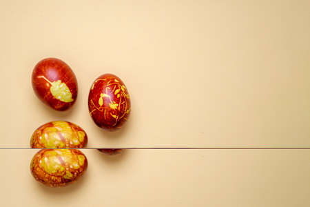 Chicken eggs colored with old-fashioned natural method by onion husks isolated on light brown. Topview of brown eggs with different natural patterns with copyspace. Traditional Easter concept.の写真素材