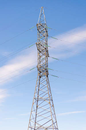 Electricity transmission power lines on the sky background. High voltage towerare on the blue. Electric power line in the middle of cloudy day. Electricity technological lines with powerful wiresの写真素材