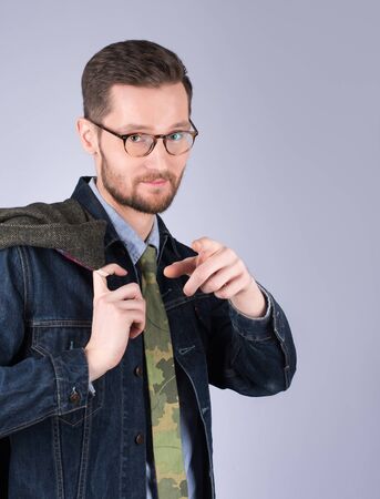 Young handsome man pointing finger. Stylish clothes, mustache and beard. Neutral grey backgroundの写真素材