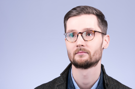 Horizontal closeup portrait of a stylish young suicine glasses. Mustache and beard, neat hair. The modern dress. Neutral grey backgroundの写真素材