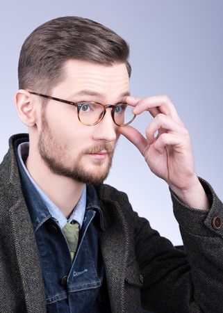 The man in glasses. Vertical portrait of a stylish clothing, beard and neat hair. Grey backgroundの写真素材