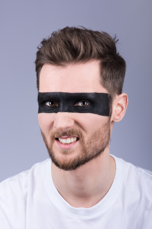 Men's fashion closeup portrait. The furious expression on his face. Stylish, modern hair and beard. White casual t-shirt. Neutral grey backgroundの写真素材