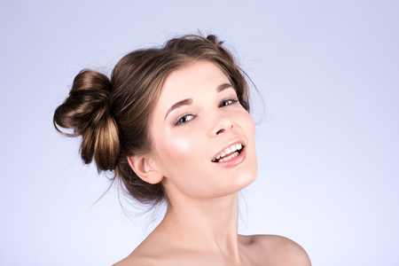 Closeup portrait. Hair twisted. Grey background. The model smilesの写真素材