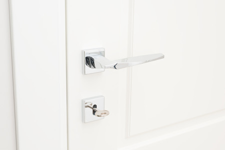 Modern glossy chrome door handle and keyhole with key. Close-up elements of the interior of the apartmentの写真素材
