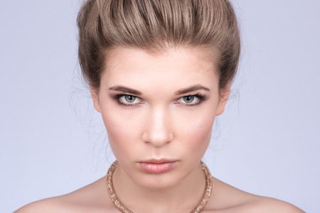 Horizontal closeup portrait of a beautiful young woman. Luxury decoration. Look at the camera. The hair is collected. Naked shoulders. Neutral grey backgroundの写真素材