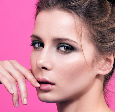 Sensual closeup portrait of a beautiful young sansinena pink background. Gentle touch fingers to face. Hair and light makeupの写真素材