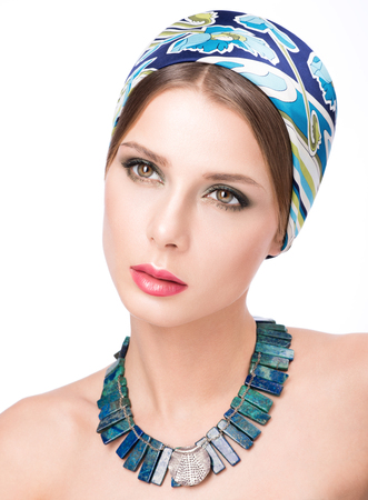 Beauty closeup portrait of beautiful young woman in a headscarf. Necklace on her neck. Makeup and clean skin. Isolated on white backgroundの写真素材