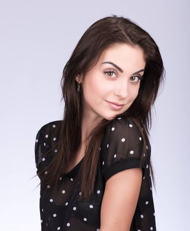 Portrait of attractive brunette on a neutral gray background. Black blouse short sleeveの写真素材
