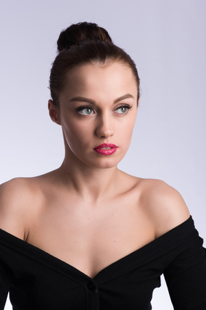 Vertical portrait of beautiful brunette in a black dress on a neutral grey backgroundの写真素材