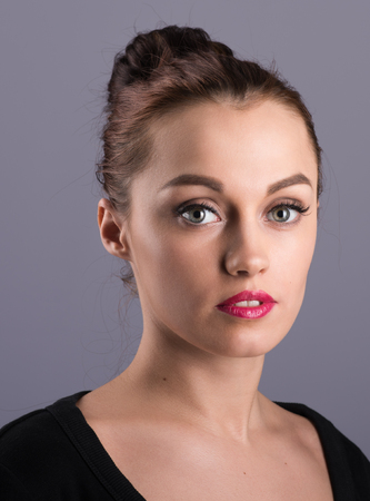 Vertical portrait of attractive brunette in a black dress on a neutral grey backgroundの写真素材