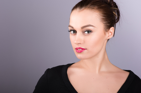 Portrait of attractive brunette in a black dress on a neutral grey backgroundの写真素材