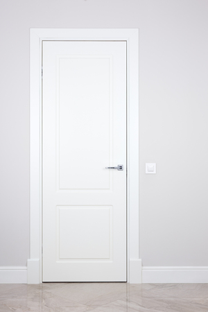 White door and switch on a light gray wall. Items bright interiorの写真素材