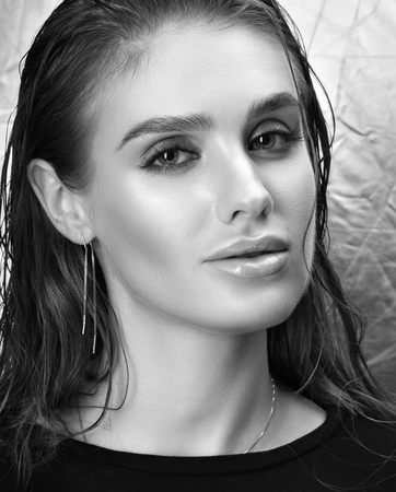 Black and white beauty portrait of beautiful young woman with professional makeup. Wet hair and clean skin. Silver backgroundの写真素材