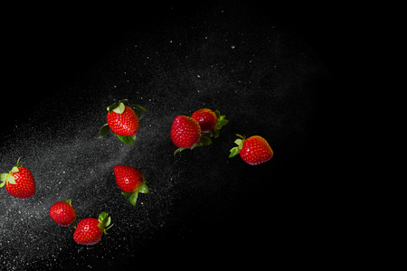 Fresh ripe strawberries flying on a black background. Stop the moment. Free spaceの写真素材